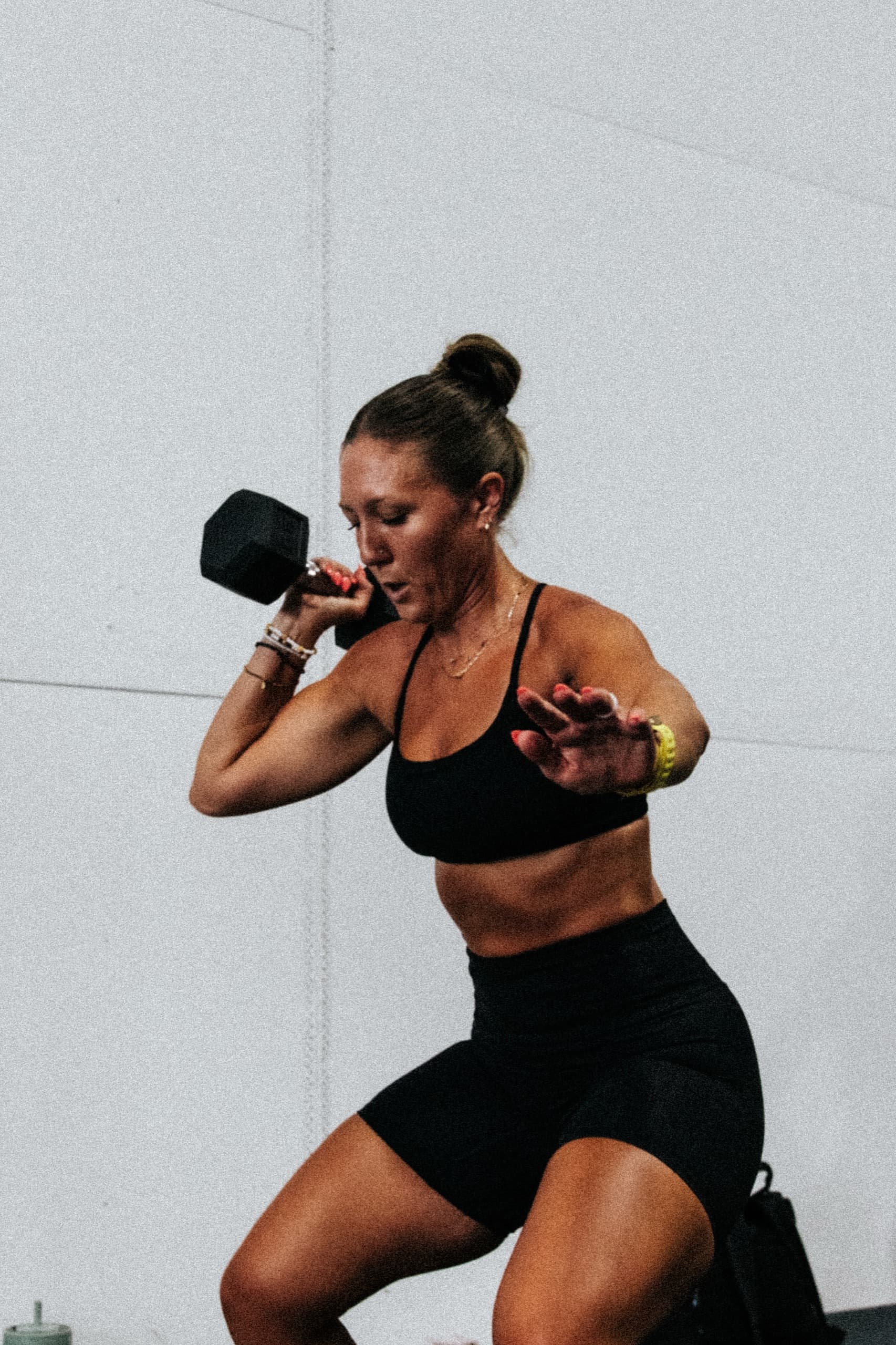 An athlete performing a dumbbell front squat against a black gym wall